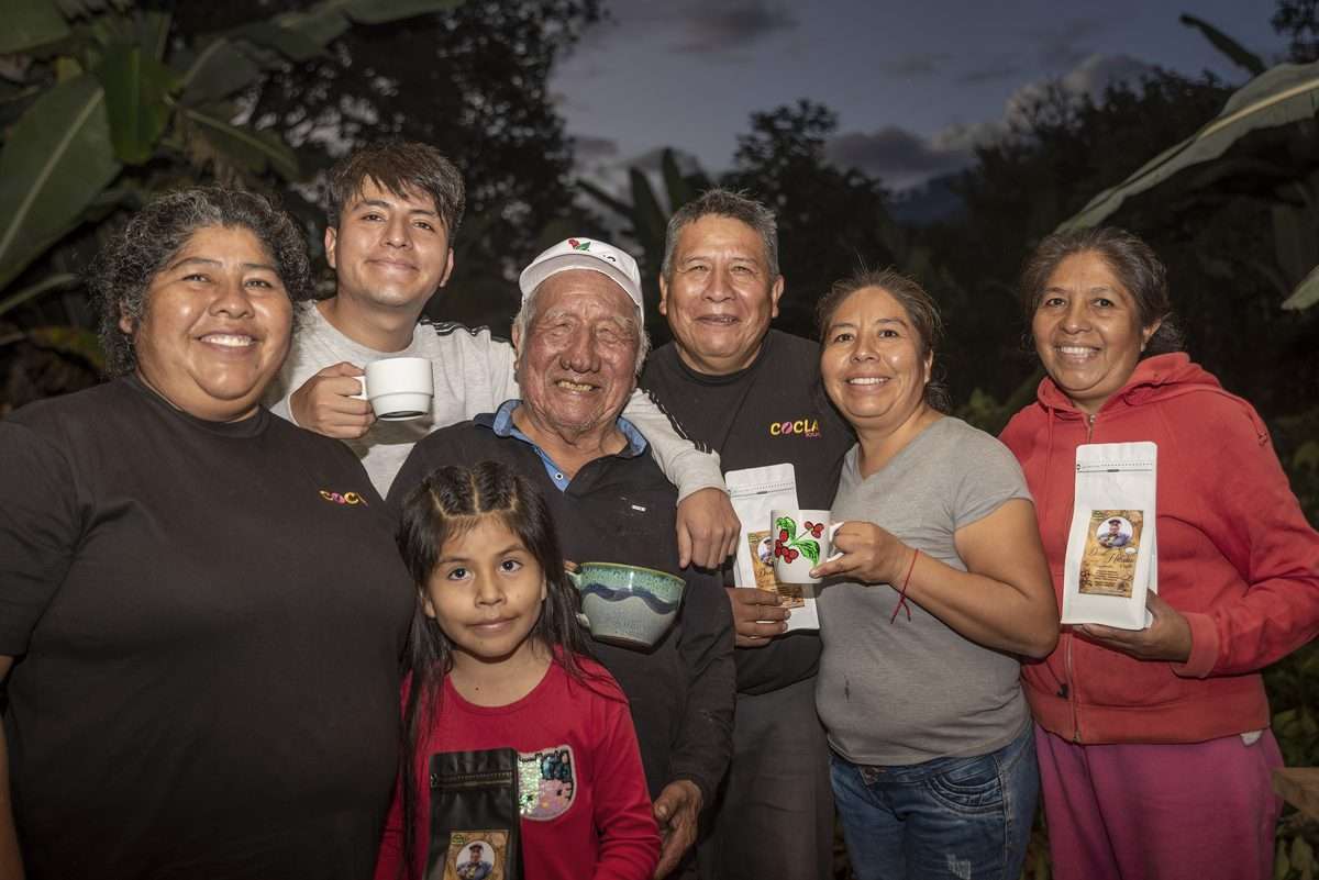 Don Hilario Pérez and his family holding cups and bags of their own coffee at their farm in the high jungle of Cusco