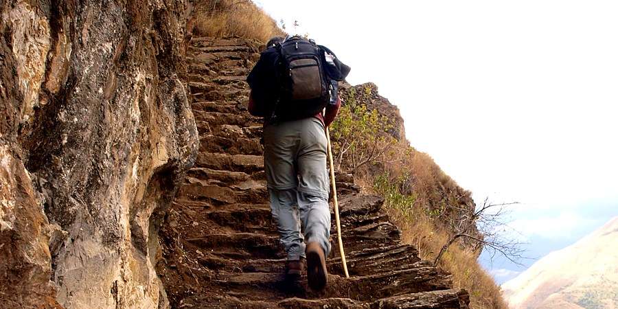 Hiker climbing the Inca stone steps carved into the rock on the Huacayupana trail